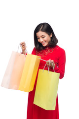 Charming Vietnamese Woman in Red Ao Dai Traditional Dress holding Shopping Bags.