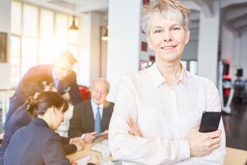 Ältere Seniorin als Geschäftsfrau vor Team