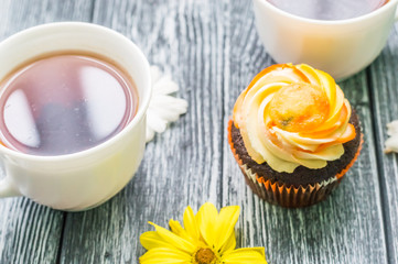 Still life with cup of tea and cake on the wooden background