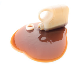 Oyster sauce poured from a bottle on a white background