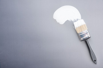 Paint brush with white paint stroke on grey  background,top view