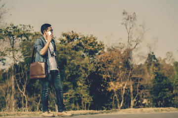 Man on smart phone and shoulder bag brown leather.