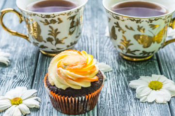 Still life with cup of tea and cake on the wooden background
