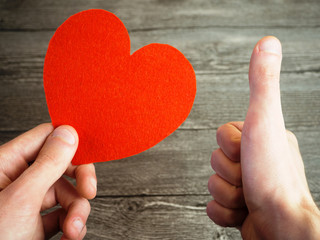 a man holds a heart in one hand and the second finger shows up. the concept