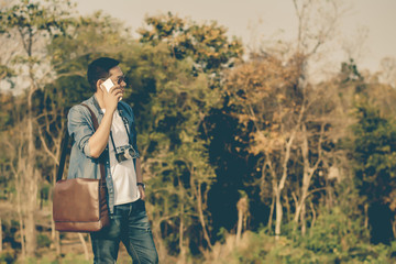 Man on smart phone and shoulder bag brown leather.