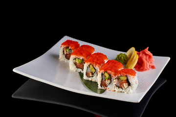 Sushi Roll with carviar and Philadelphia cheese with vasabi, pickled ginger and lemon slice on white plate on black background