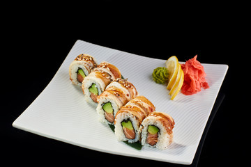Sushi Roll withsalmon avocado and sesame with vasabi, pickled ginger and lemon slice on white plate on black background