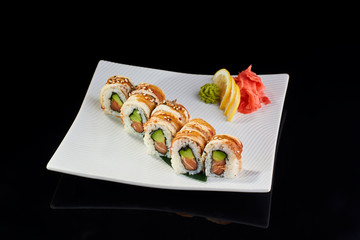 Sushi Roll withsalmon avocado and sesame with vasabi, pickled ginger and lemon slice on white plate on black background