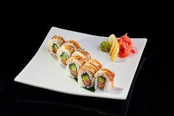 Sushi Roll withsalmon avocado and sesame with vasabi, pickled ginger and lemon slice on white plate on black background
