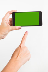 Close up of young caucasian female hands holding modern smartphone with green touch screen isolated on white background. Vertical color photo.