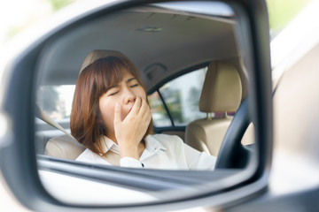 Closeup portrait sleepy, tired young woman driving her car after long hour trip in mirror, Sleep deprivation, accident concept.