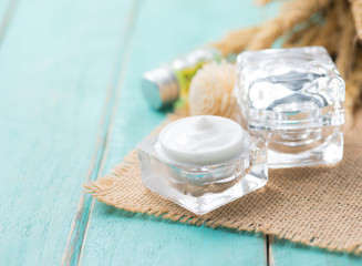 Moisturizing face cream in open glass jar on wood