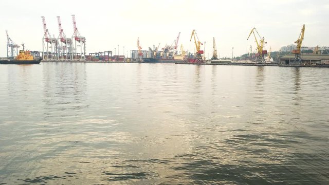 Tugboat and harbor cranes. Port at daytime. Marine industry jobs.