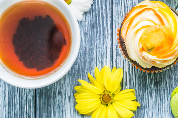 Still life with cup of tea and cake on the wooden background