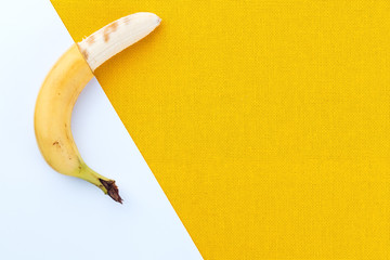 Half-cleaved yellow ripe bananas from the tropics on a white and yellow fabric background with...