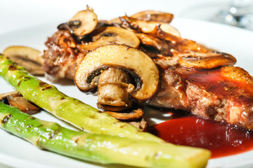 steaks with mushrooms and green asparagus on a plate, selective focus, closeup
