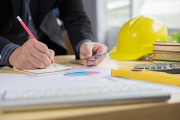 Architects working on blueprint with pencil,engineer inspective in workplace ,architectural project, blue prints,ruler,calculator,laptop and yellow helmet. Construction concept. Engineering tools