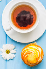 Still life with cup of tea and cake on the wooden background