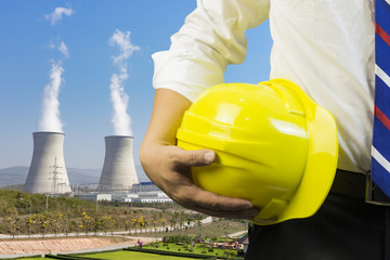 engineer or worker hold in hand yellow helmet ,Engineer and worker discussing blueprint next to electrical substation for workers security in front of construction blur background. Selective focus.