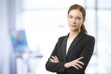 Confident professional woman. Shot of a smiling young businesswoman standing in the office with arms crossed. 