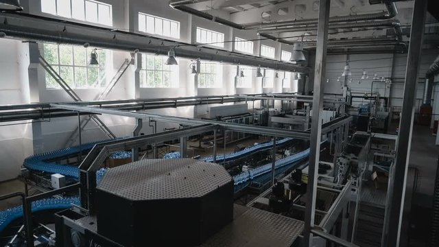 Wide shot of water filling line - Water bottling line for processing and bottling pure mineral water into blue bottles.