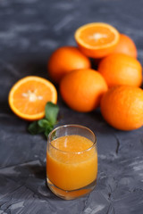 Orange juice in a glass and oranges on a concrete background