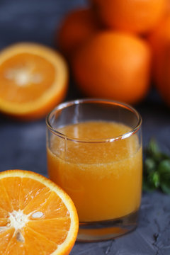 Orange juice in a glass and oranges on a concrete background
