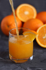 Orange juice in a glass and oranges on a concrete background