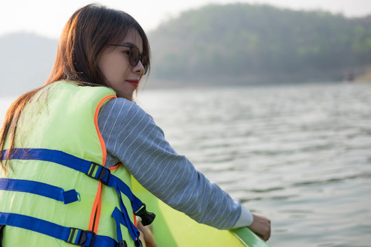 young woman equip life jacket sitting relaxing on prow. she looking side around herself have sea and sunset background.this image for nature,travel and portrait