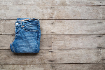 Top view, Roll and Jeans stacked on a wooden background.