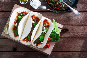 mexican steak and chicken fajitas in cast iron skillet shot top down with corn tortillas