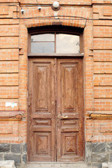 Old wooden door to house with brick wall. Entrance door to old house.