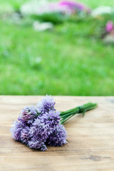 Flower chives tied in a snop on a natural wooden cutting board © Miroslav Beneda