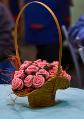 Composition "Tea roses in a woven straw basket"/On the table stands a woven straw basket with a high handle. In the basket a bouquet of artificial tea roses is gently pink.