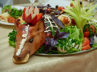 Suckling pig with greenery on festive table.