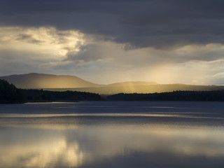 Sonnenstrahlen am Gewitterhimmel an einem See
