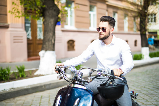 Handsome bearded young man riding blue scooter.