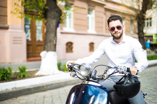 Portrait of serious young businessman on motorbike on city street
