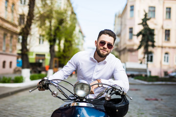 Young man in sunglasses riding scooter along the street city