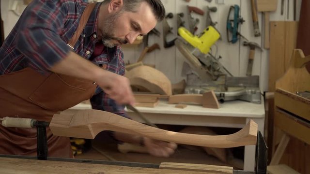 Cabinet Maker Polishes Cabrioli Leg in his Workshop/Cabinet maker polishes the cabriolet leg with a file. He works in a small family joiner’s shop
