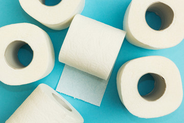 Scattered rolls of white toilet paper on a blue background.