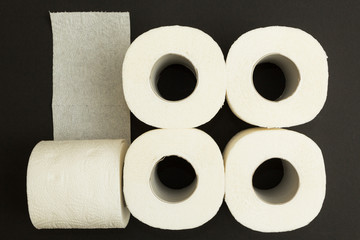 Rolls of white toilet paper on a black background, concept.