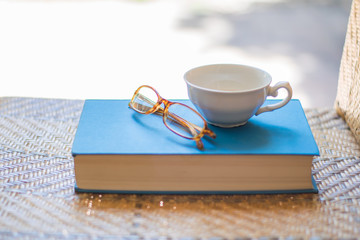 Book, cup and eyeglasses on a chair.