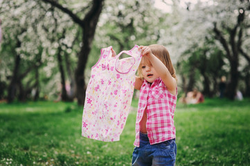 cute little toddler girl getting dressed and changing clothes outdoor