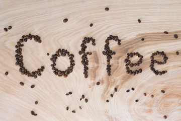 Word coffee laid out from grains on a wooden background