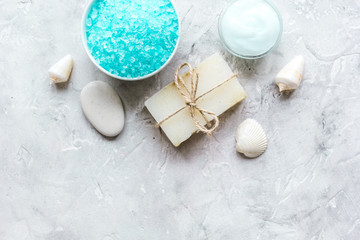 Fototapeta na wymiar blue salt, body cream and shells for spa bath background top view mockup