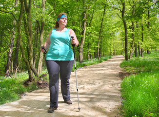 Overweight woman walking on forest trail. Slimming and active lifestyle theme. 