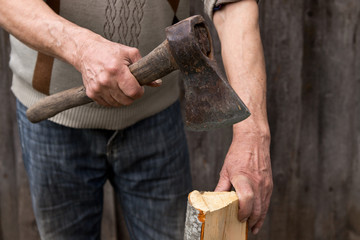 Worker, an elderly man with an old axe chops firewood. Forced to work in retirement . Employee .