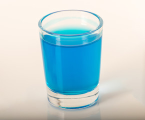 Single glass of blue drink kamikaze, thick glass, closeup, blue shot