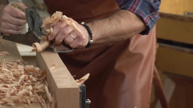Joiner Planes Solid Wood in his Workshop/Cabinet maker planes the beech plank with a plane. He works in a small family joiner&rsquo;s shop. Slow motion